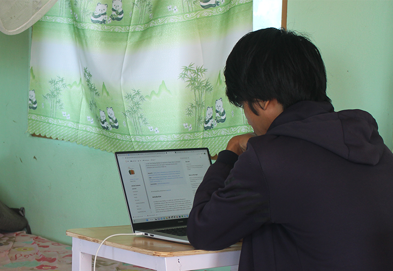 Student studying at his laptop in his bedroom